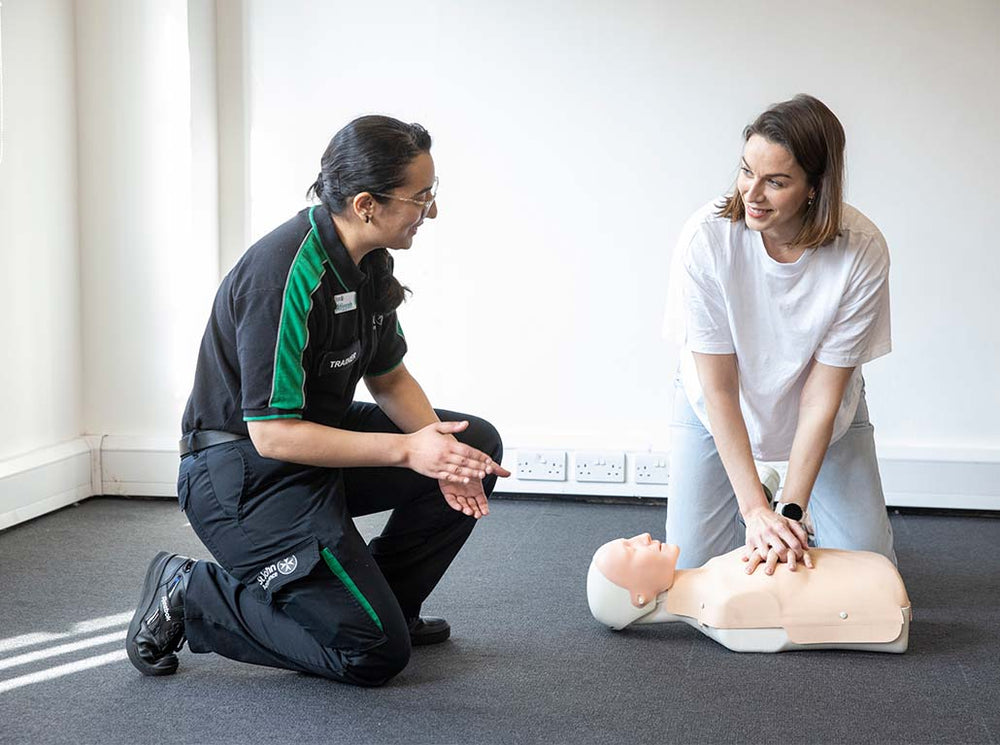 man teaching a woman CPR in a class room