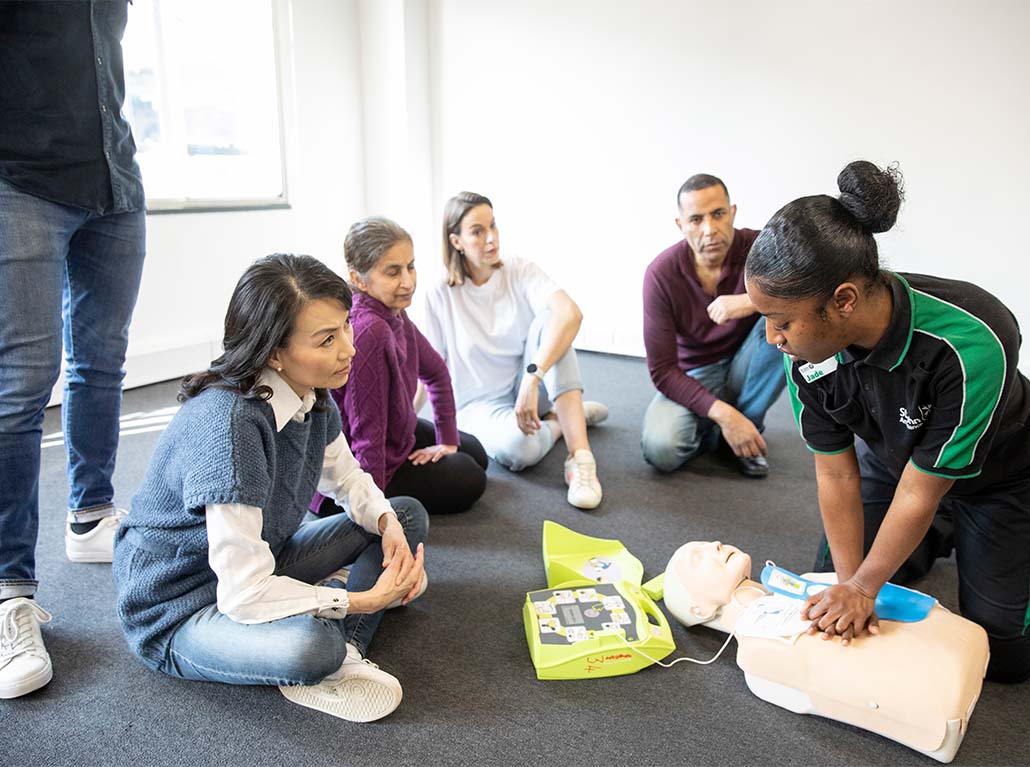 classroom of student undertaking a first aid course with a manikin and defbrillator