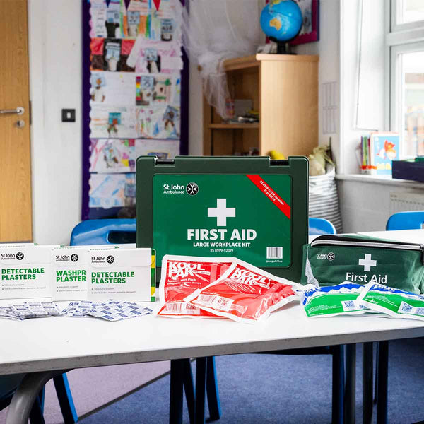 First aid kit on a table with first aid supplies showing in a school classroom