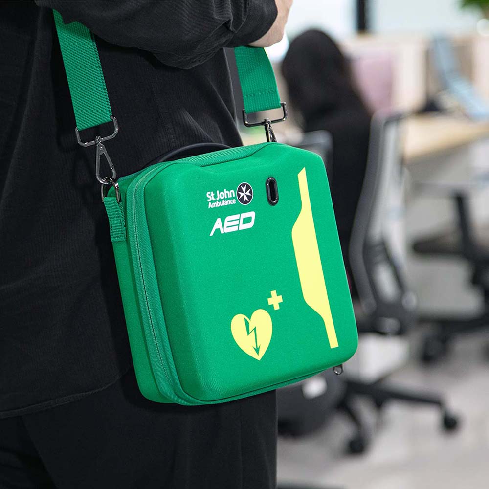 A practical use of the St John Ambulance HEART Hardcase - a person carrying it in an office environment.