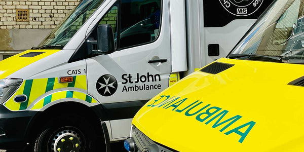 Two ambulance vehicles, one with 'St John Ambulance' branding and the other with 'NHS' branding, parked side by side.