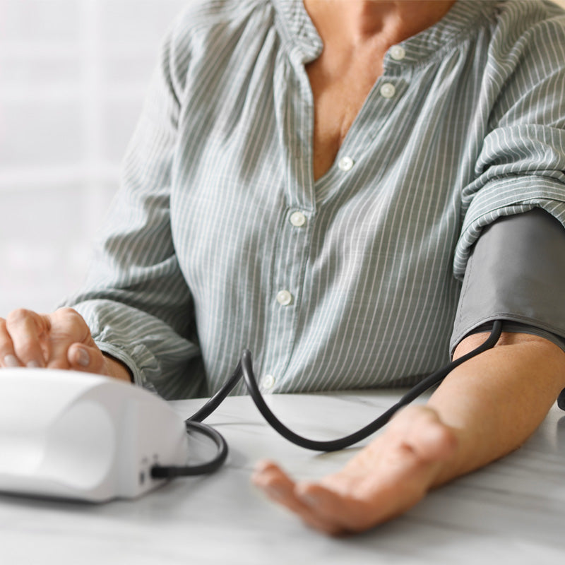 Person having their blood pressure taken with a device on a white surface