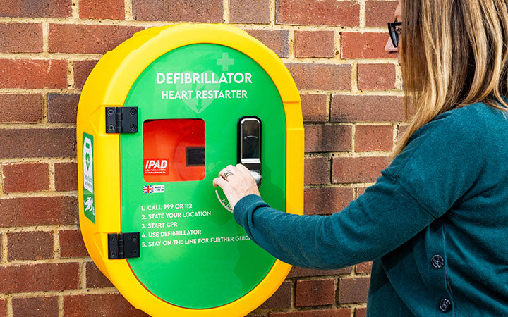 Defibrillator Accessories, picture shows lady opening a wall cabinet.