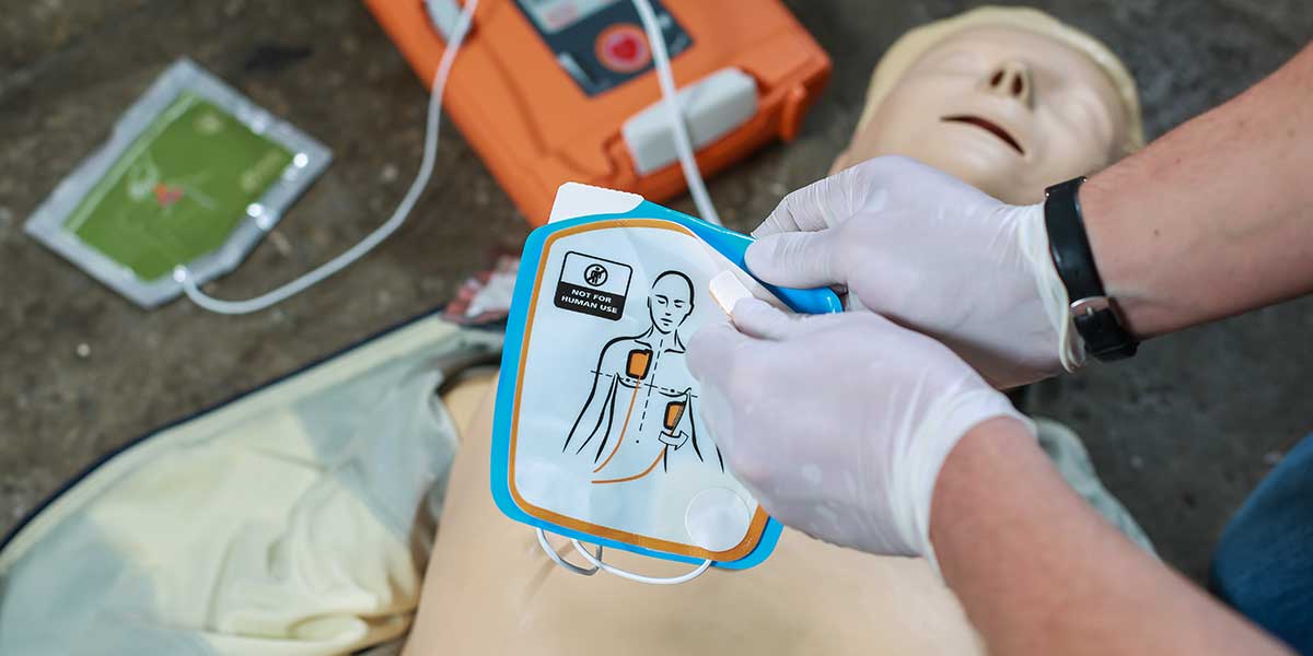 Person using an AED accessories on a mannequin with a focus on CPR technique.