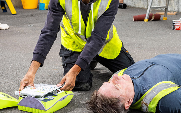 Person performing CPR on another person on a street.