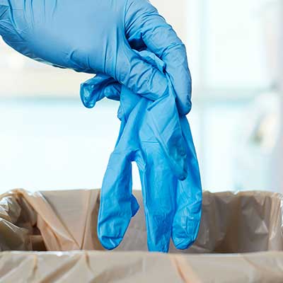 Blue gloves being worn by a hand with a blurred background