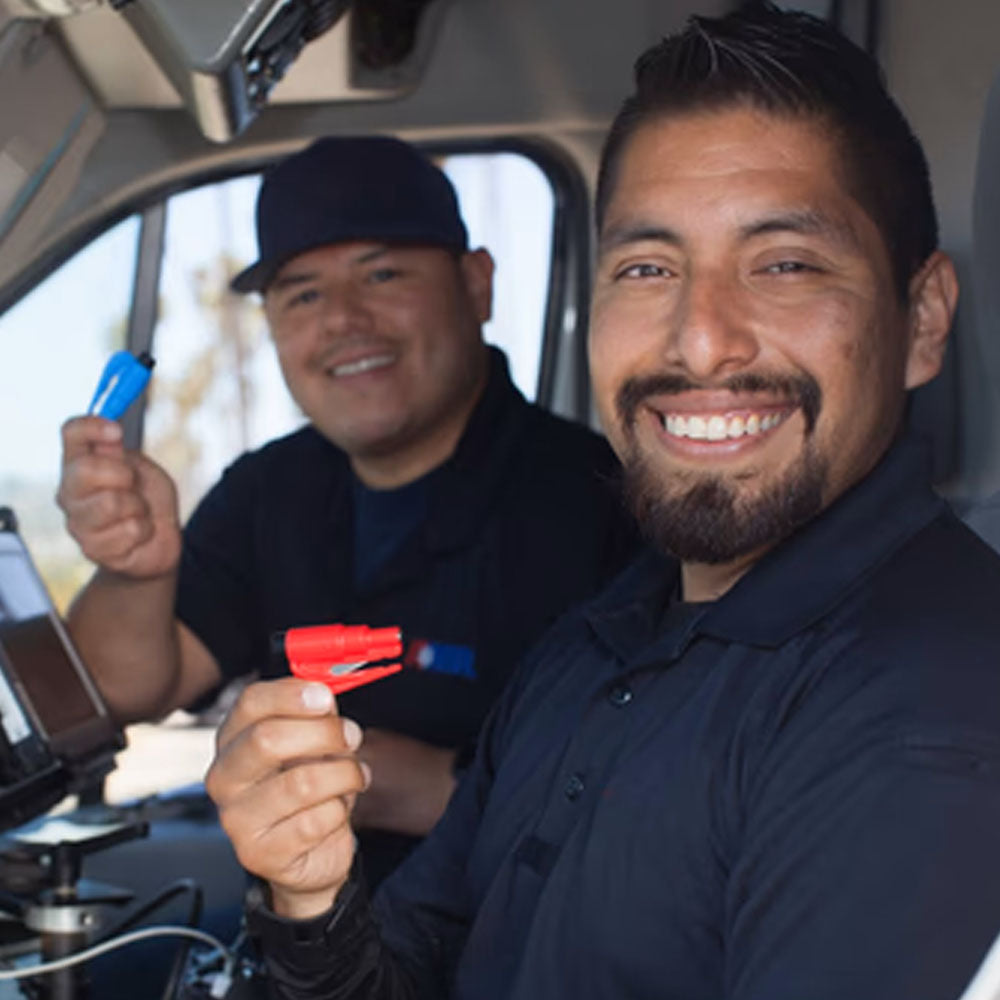 Two workers inside their lorry, each holding a ResQMe 2-in-1 Rescue Tool.