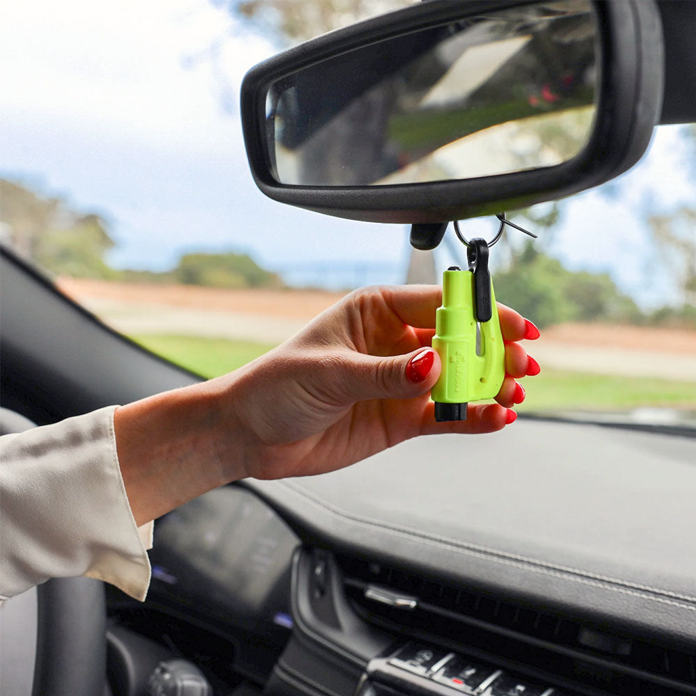 A woman attaching a ResQMe 2-in-1 Rescue Tool to her rear-view mirror.
