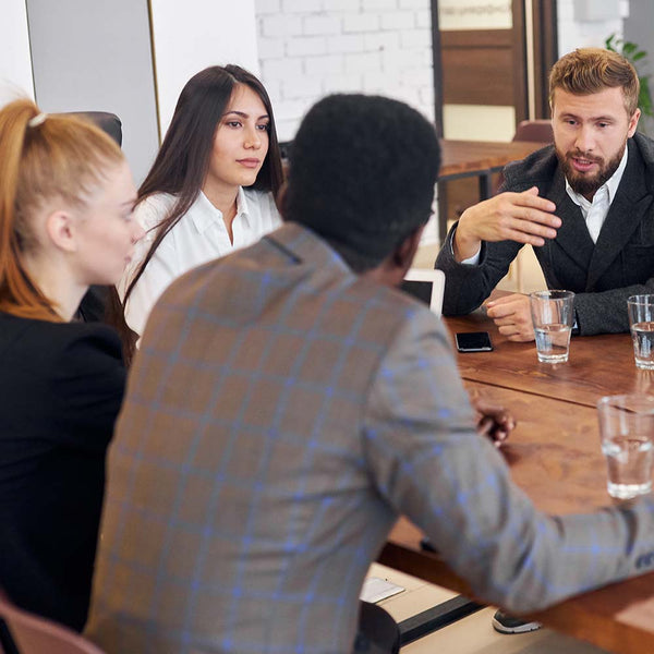 Employees sat around a desk, speaking to each other.