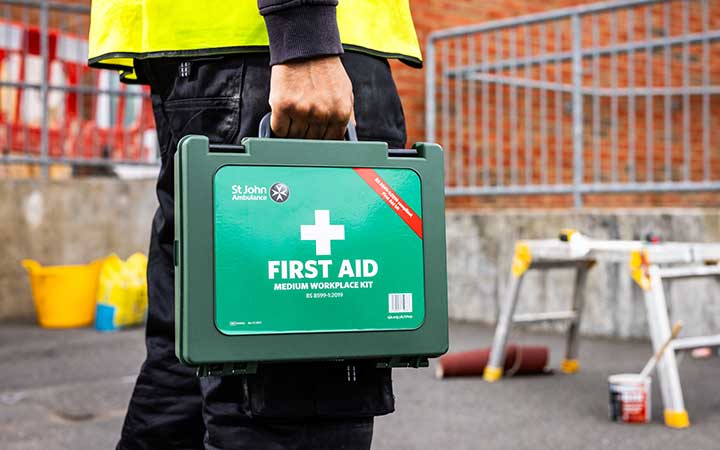 Construction worker carrying a first aid kit on a building site
