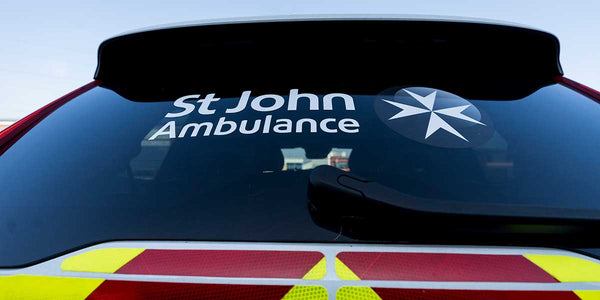 St John Ambulance logo on a vehicle's windshield with a clear blue sky background
