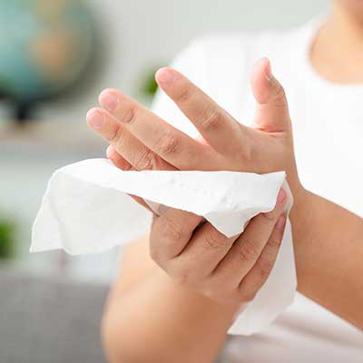 Person using a tissue to clean hands with a blurred background