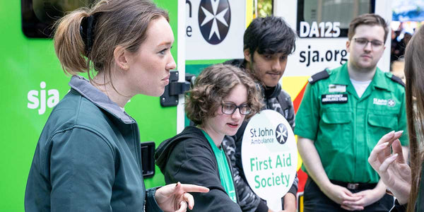 Group of people in front of a St. John Ambulance vehicle